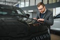 Making his choice. Horizontal portrait of a young man in a suit looking at the car and thinking if he should buy it Royalty Free Stock Photo