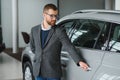 Making his choice. Horizontal portrait of a young man in a suit looking at the car and thinking if he should buy it Royalty Free Stock Photo