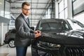 Making his choice. Horizontal portrait of a young man in a suit looking at the car and thinking if he should buy it Royalty Free Stock Photo