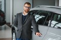 Making his choice. Horizontal portrait of a young man in a suit looking at the car and thinking if he should buy it Royalty Free Stock Photo