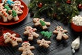 Making homemade Christmas cookies. Gingerbread people and festive decor on black table