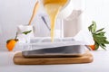 Making homemade citrus sponge cake. Dough is poured into baking sheet. Orange biscuit on white table Royalty Free Stock Photo