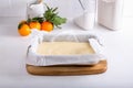 Making homemade citrus sponge cake. Orange biscuit dough in baking sheet, on white table Royalty Free Stock Photo