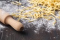 Making homemade pasta linguine on rustic kitchen table with flour, vintage sieve and cutting board