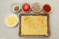 Making Homemade Rectangular Pizza - Ingredients in top view: Cheese, oregano, tomato, tuna, sauce dough