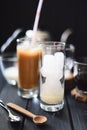 Making iced coffee. Tall glass with ice cubes and condensed milk ready for pouring coffee on black background Royalty Free Stock Photo