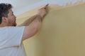 Making interior change preparing for home repair work man standing on metal ladder and tearing off old wallpaper from wall in room Royalty Free Stock Photo