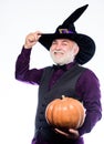 Making jack o lantern. mature man magician in witch hat. bearded man ready for halloween party. evil wizard hold orange