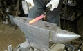 Making the knife out of metal at the forge. Close up blacksmith`s hands hitting hot metal with a massive hammer on an