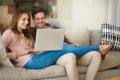 Making light work of the monthly budget. a happy young couple using a laptop together while relaxing on the sofa at home Royalty Free Stock Photo