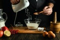 Making a milk dessert on the kitchen table. An electric mixer in the hands of the chef and a slurry with sugar Royalty Free Stock Photo