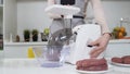 Making minced meat in electric meat grinder from fresh beef at home. Electric mincer machine with fresh chopped meat Royalty Free Stock Photo