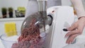 Making minced meat in electric meat grinder from fresh beef at home. Electric mincer machine with fresh chopped meat Royalty Free Stock Photo