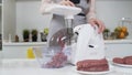 Making minced meat in electric meat grinder from fresh beef at home. Pile of chopped meat. Electric mincer machine with