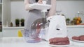 Making minced meat in electric meat grinder from fresh beef at home. Pile of chopped meat. Electric mincer machine with