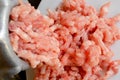 Making minced meat with a meat grinder and red raw mince on a white plate, top view