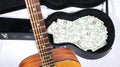 Acoustic guitar neck up close and out of focus, full guitar case with money in focus, sharp depth of field