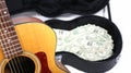 Partial acoustic guitar in focus, case with money out of focus, sharp depth of field