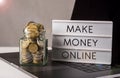 Making money online banner with gold coins filled jar on laptop Royalty Free Stock Photo