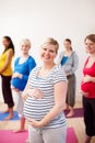 Making the most of maternity. A multi-ethnic group of pregnant women standing in an exercise class smiling happily at