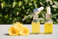 Making natural herbal cosmetics at home - dropper bottles with calendula oil against green leaves