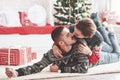 Making photo of cute kiss. Lovely young couple lying on the floor of living room at new year time with gift boxes