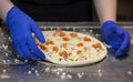 Making pizza in a restaurant, chef hands in gloves