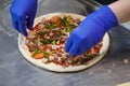 Making pizza in a restaurant, chef hands in gloves