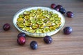 Making of plum pie with the dough and sliced fresh plums in a glass pan Royalty Free Stock Photo