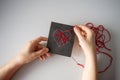 Making a postcard with a heart using thread printing on black cardboard