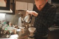 Making pourover coffee. Nice barista preparing coffee drink, looking concentrated. Focused coffee shop owner is pouring water into Royalty Free Stock Photo