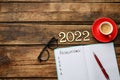 Making resolutions for 2022 New Year. Flat lay composition with notebook on wooden table Royalty Free Stock Photo