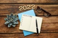 Making resolutions for 2022 New Year. Flat lay composition with notebook on wooden table Royalty Free Stock Photo