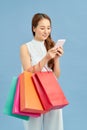 Making the retail connection. Beautiful young woman with shopping bags using her smart phone with smile while standing Royalty Free Stock Photo