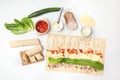 Making rolled wrap at home from flat lavash bread. Different ingredients around on white table. Royalty Free Stock Photo