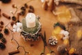 Making rustic christmas candle decor. Christmas candle in rustic holder made of branches, cotton, anise and pine cones on wooden Royalty Free Stock Photo