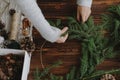 Making rustic christmas wreath flat lay. Female hands holding fir branches on wooden table Royalty Free Stock Photo