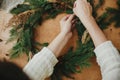 Making rustic Christmas wreath flat lay. Hands holding berries and  fir branches, pine cones, thread on wooden table. Christmas Royalty Free Stock Photo
