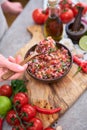 making salsa dip sauce - woman mixing chopped ingredients in wooden bowl
