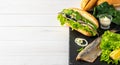 Making a sandwich of herring fillet with onions, cucumber and salad on a stone board. White wooden background with copy space. Royalty Free Stock Photo