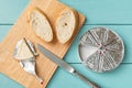 Making sandwich with processed cream cheese and sliced bread on a cutting board over blue wooden table. Small triangular pieces of