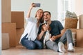 Making selfie. Young couple with dog are moving to new home Royalty Free Stock Photo