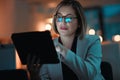 Making smart night time business moves. a businesswoman using a digital tablet during a late night at work.