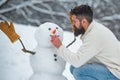 Making snowman and winter fun for man. Winter man. Happy father playing with a snowman on a snowy winter walk. Young