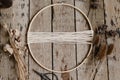 Making stylish boho autumn wreath with dry flowers flat lay. Wooden hoop, thread, scissors, and dry herbs on rustic wooden