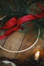 Making stylish modern christmas wreath. Fir branches, round wooden hoop, red ribbon, candle and pine cones on rustic table. Royalty Free Stock Photo