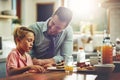 Making sure his son has a good breakfast. a man sitting with his son while hes having breakfast. Royalty Free Stock Photo