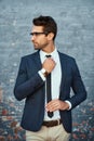 Making sure he looks his best. a handsome young businessman adjusting his tie while standing against a grey facebrick Royalty Free Stock Photo