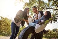 Making sure their earliest memories will be good ones. a happy mother and father pushing their daughters on a tyre swing