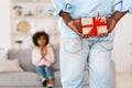 Making surprise birthday gift. Granddad hiding present for granddaughter behind his back, selective focus. Blank space Royalty Free Stock Photo